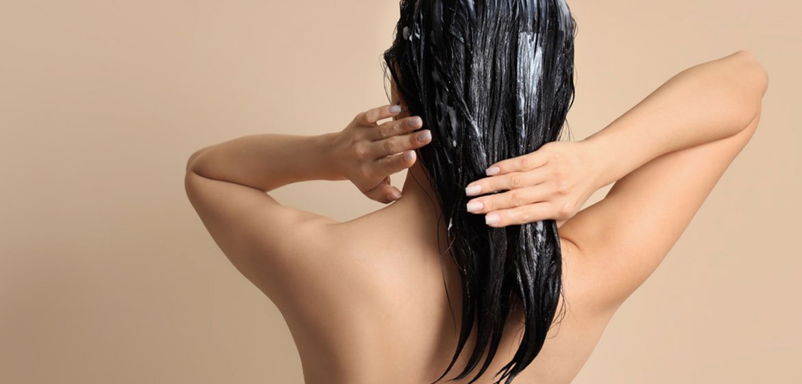 Schulterbereich einer Frau von hinten, die sich ihre Haare wäscht, von hinten betrachtet